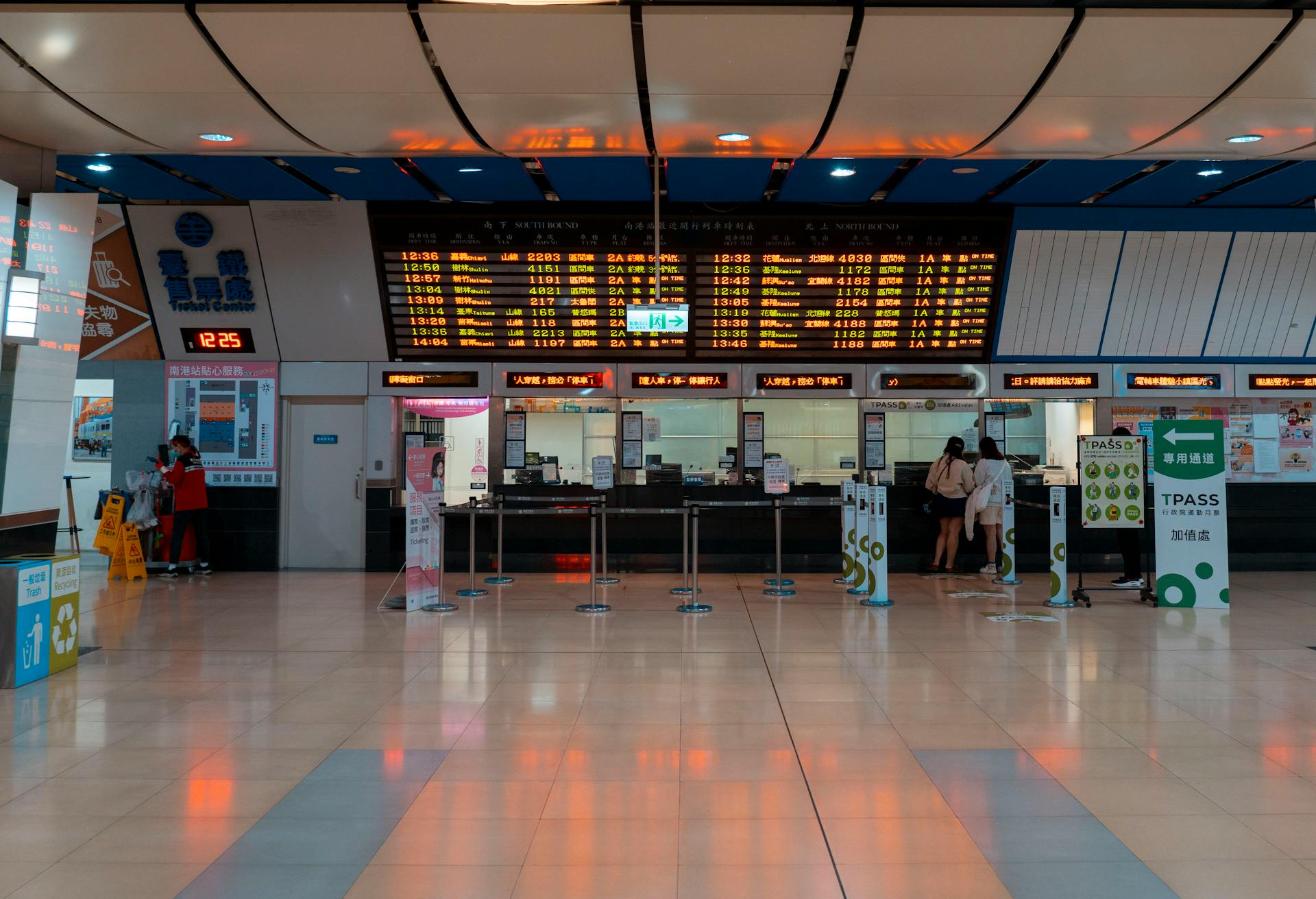 Interior of a train station with a digital timetable and ticket counters.