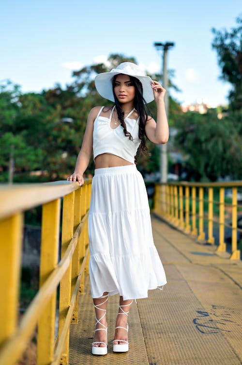 Brunette Woman with Hat in White Top Posing on Footbridge