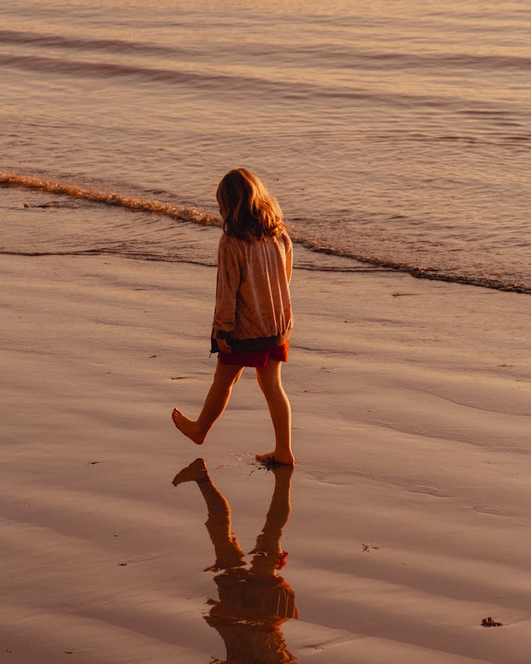 Little Girl Walking On Wet Beach Sand