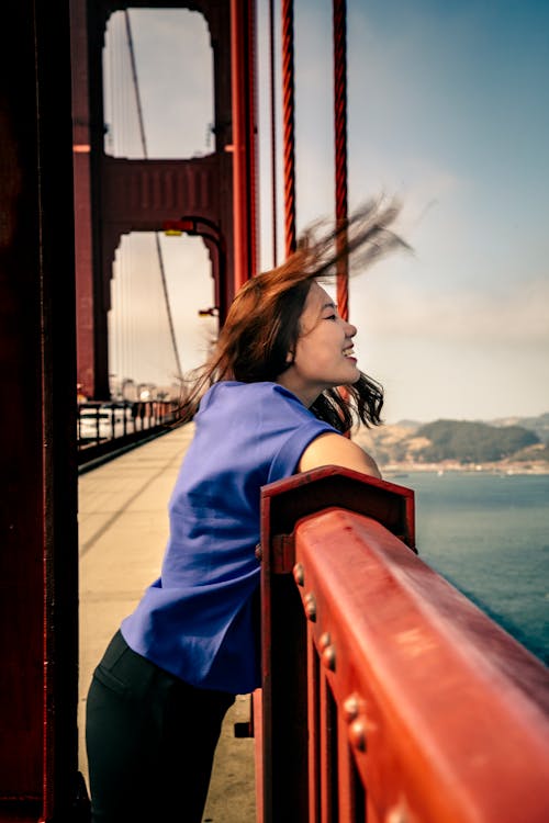 Smiling Woman Leaning on Railing of Golden Gate Bridge in San Fran