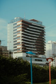 A striking high-rise building in an urban area, showcasing modern architectural design with green surroundings.