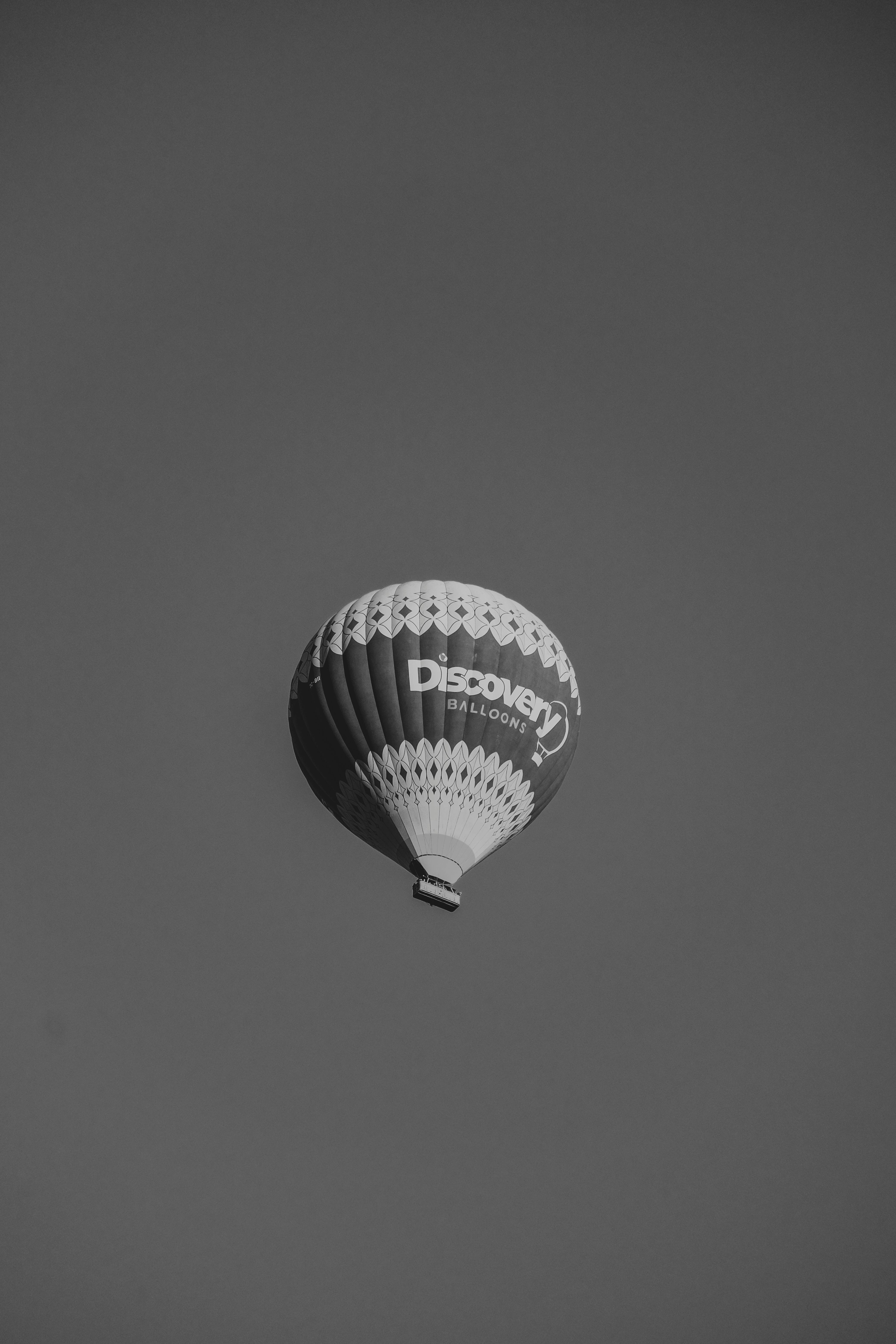 A single hot air balloon soars against a monochrome sky, showcasing aviation freedom.