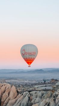 A hot air balloon soars over the unique rock formations of Cappadocia at sunrise, Turkey.