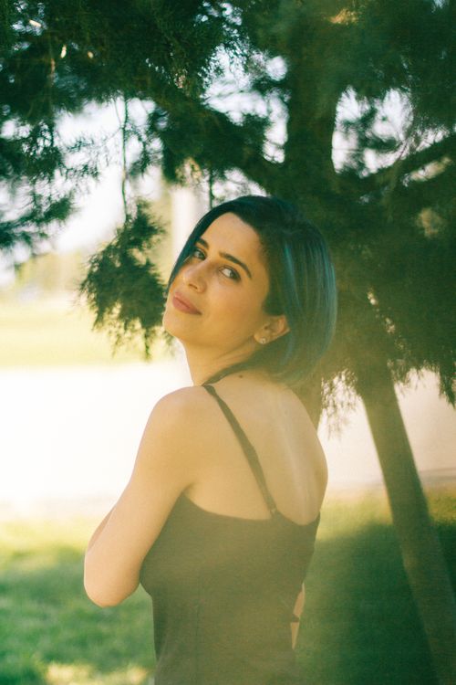Free A serene portrait capturing a woman posing gracefully amidst sunlit greenery. Stock Photo