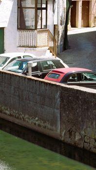 A serene urban scene of parked cars by a canal in Aveiro, Portugal.