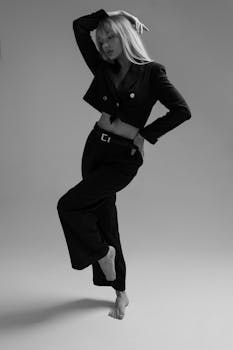 Elegant black and white studio portrait of a barefoot woman in a fashion outfit.