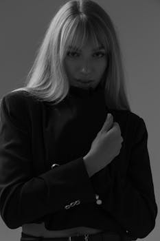 Stylish black and white portrait of a woman posing elegantly in a studio setting with dramatic lighting.