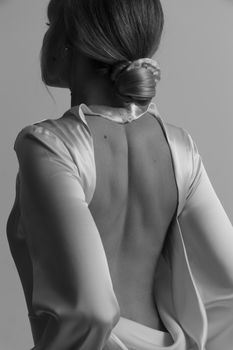 Black and white image of an elegant woman in a stylish open-back dress showcasing modern fashion.