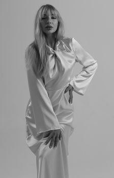Graceful woman posing in satin dress in a studio fashion shoot.