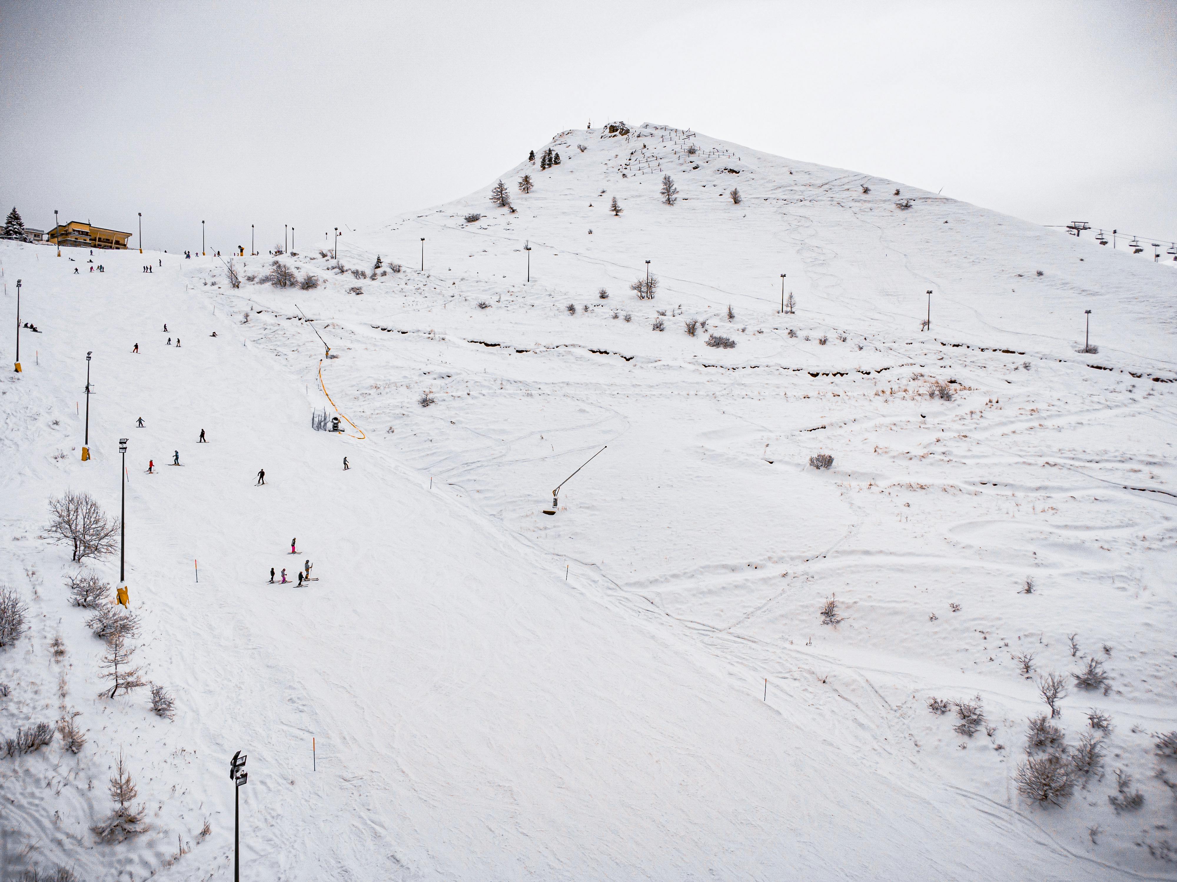 An aerial shot of a ski slope with skiers enjoying a winter day on the snow-covered hill.