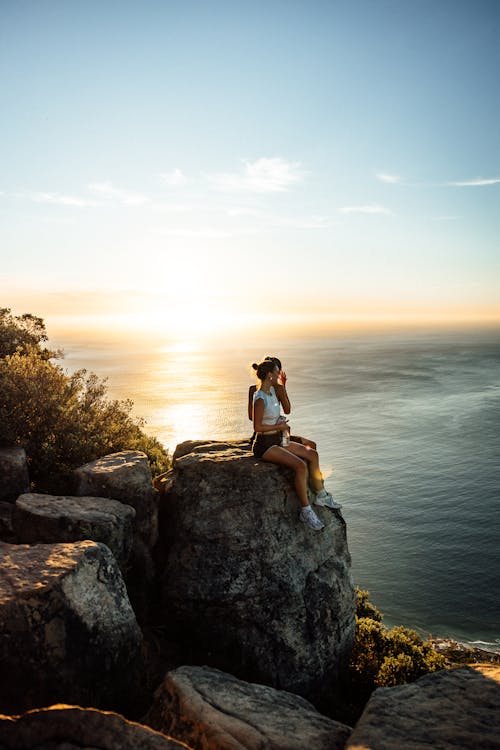Sitting on a Rock Overhang of a Seaside Cliff at Sunset