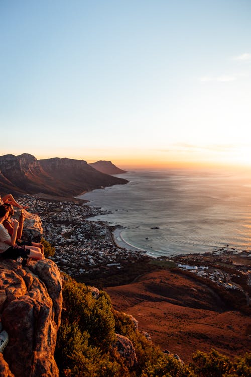 Young Tourists Watching the Sunset While Sitting on a Mountain Above Cape Town