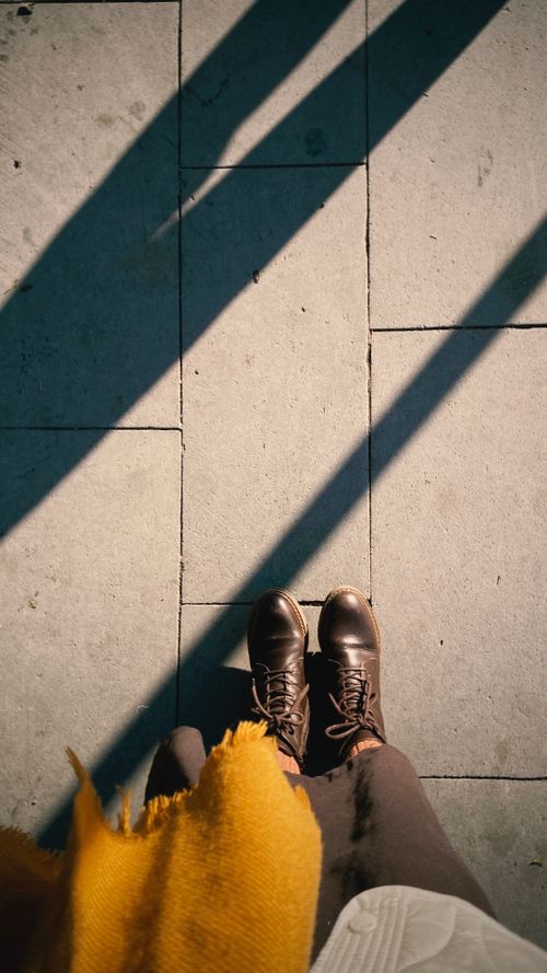 Free Brown boots and a scarf casting shadows on a sunlit sidewalk, capturing the essence of fall fashion. Stock Photo