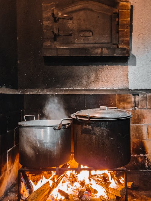 Two old, rusty pans simmering on a rustic fireplace of a Portuguese rural kitchen, creating a nostalgic scene of traditional cooking and homely warmth
