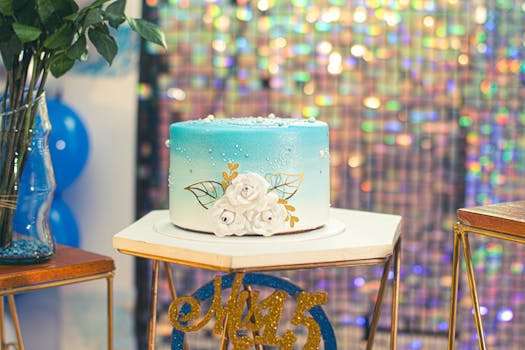 A blue gradient birthday cake with floral decorations on a festive table setup, perfect for celebrations.