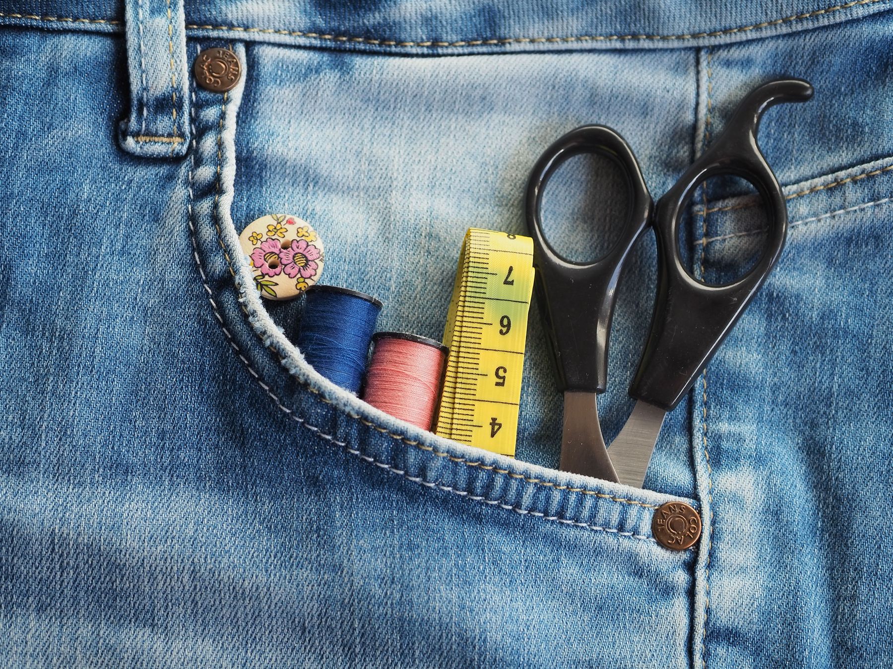 Scissors, thread and a tape measure ready for a clothing repair