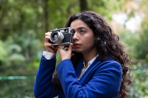 Young Woman Taking Pictures with a Film Camera in a Park 