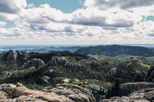 Free Breathtaking panoramic view of a mountain range with lush forests and rocky formations under a cloudy sky. Stock Photo
