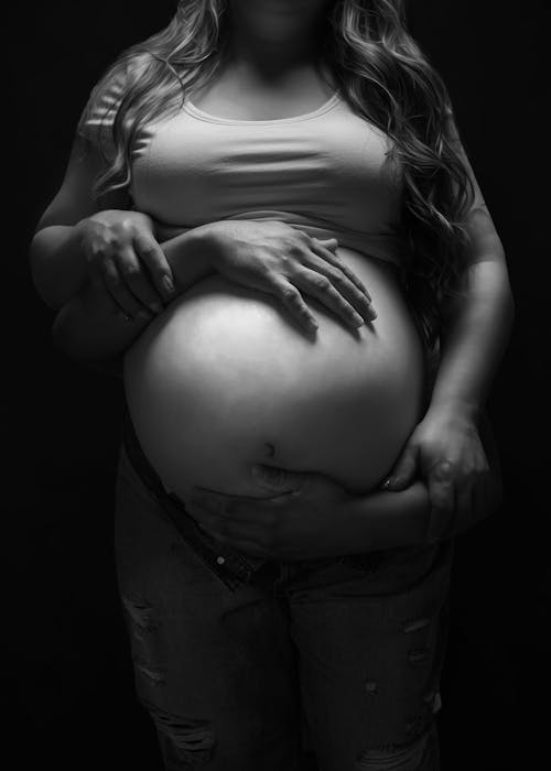 Black and White Studio Shot of Couple Touching the Stomach of the Pregnant Woman 