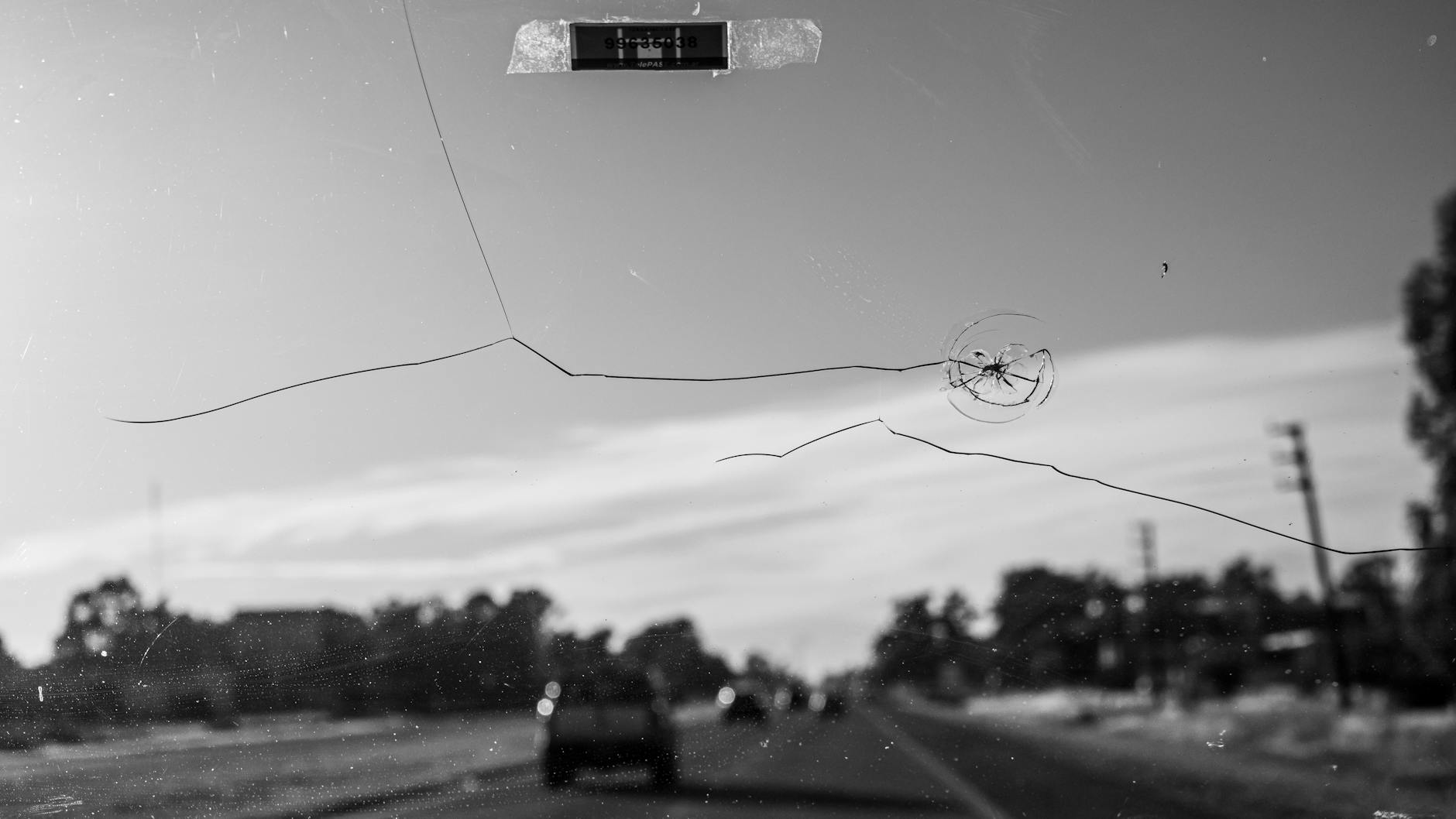 Black and white shot of a cracked windshield, driving on a Buenos Aires road.