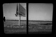 Black and white view of a rural billboard in Buenos Aires countryside through a window.