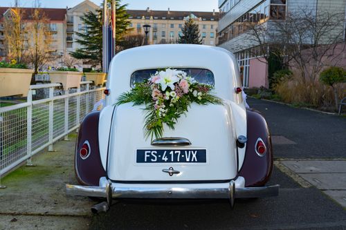 Free Elegant vintage car with floral decoration parked on city street, perfect for wedding themes. Stock Photo