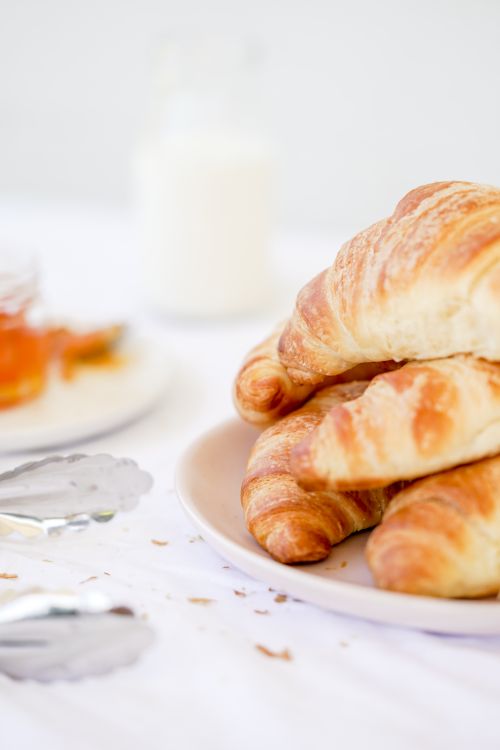 Free Appetizing croissants on a plate accompanied by milk and honey, perfect for a breakfast setting. Stock Photo