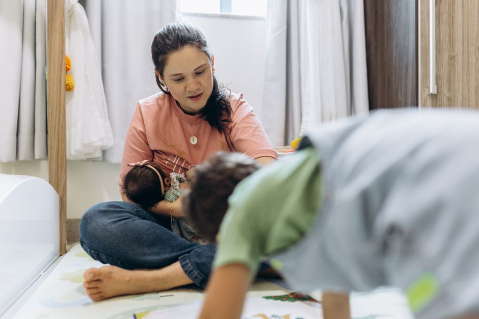 Como a Criatividade Pode Melhorar sua Rotina de Maternidade 2 A mother enjoying playtime with her children at home in a cozy room setting.
