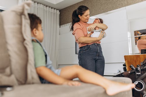 Mother with Baby behind Sitting Son on Couch