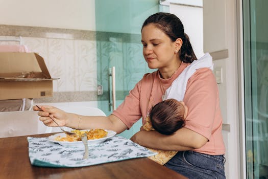A mother eating at the table while holding her baby, depicting a warm family moment.
