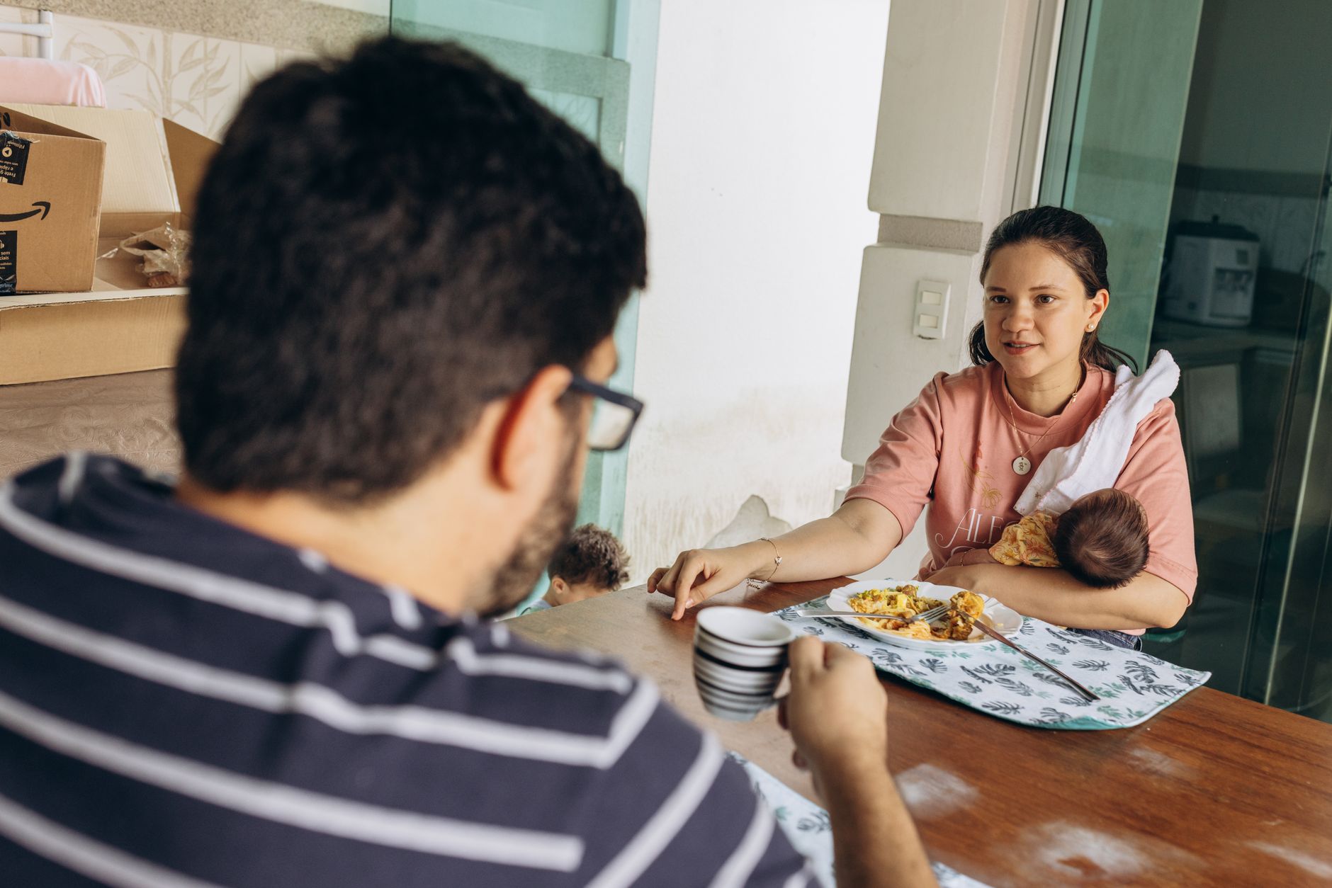 Casal com recém-nascido a conversar em ambiente doméstico acolhedor