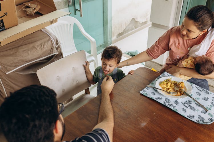 Mother And Father With Son And Baby By Table