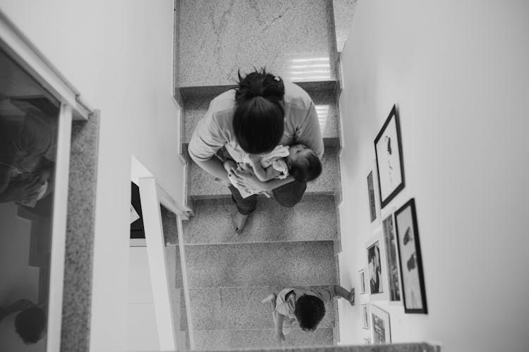 Mother Walking Down Stairs With Baby In Arms