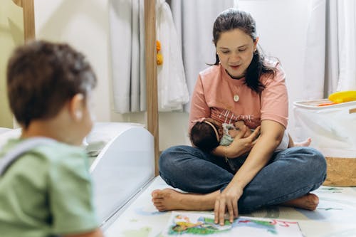 Mother Sitting and Holding Baby and Playing with Son