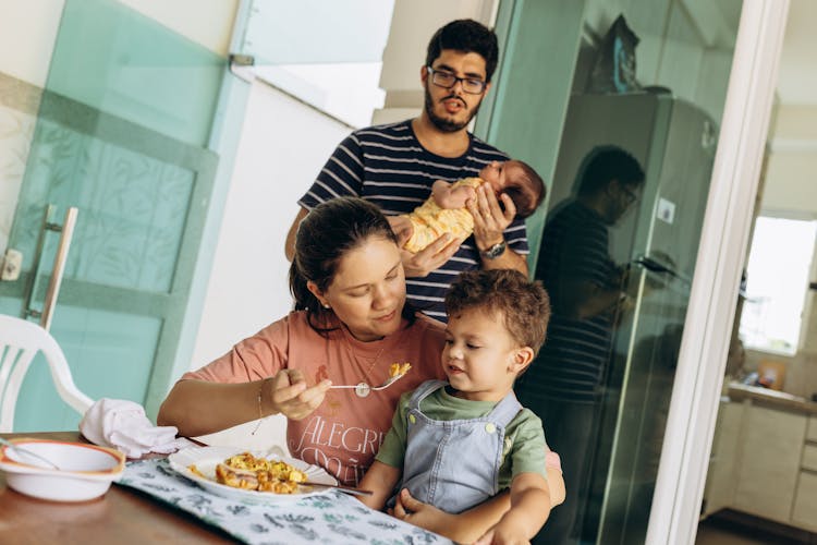 Mother Feeding Boy And Father Carrying Baby