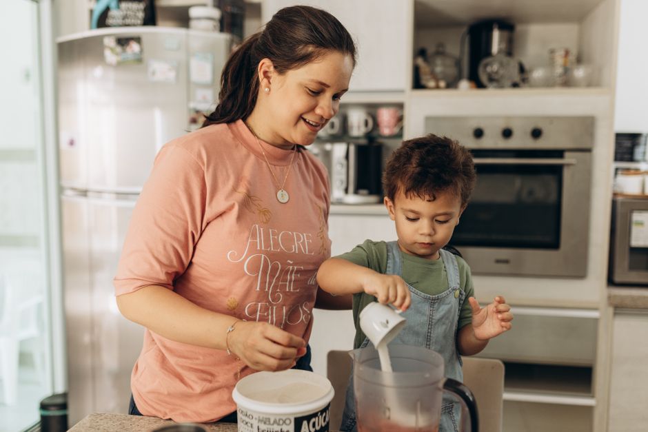 A joyful mother and son team up in the kitchen, enjoying a fun cooking session together.