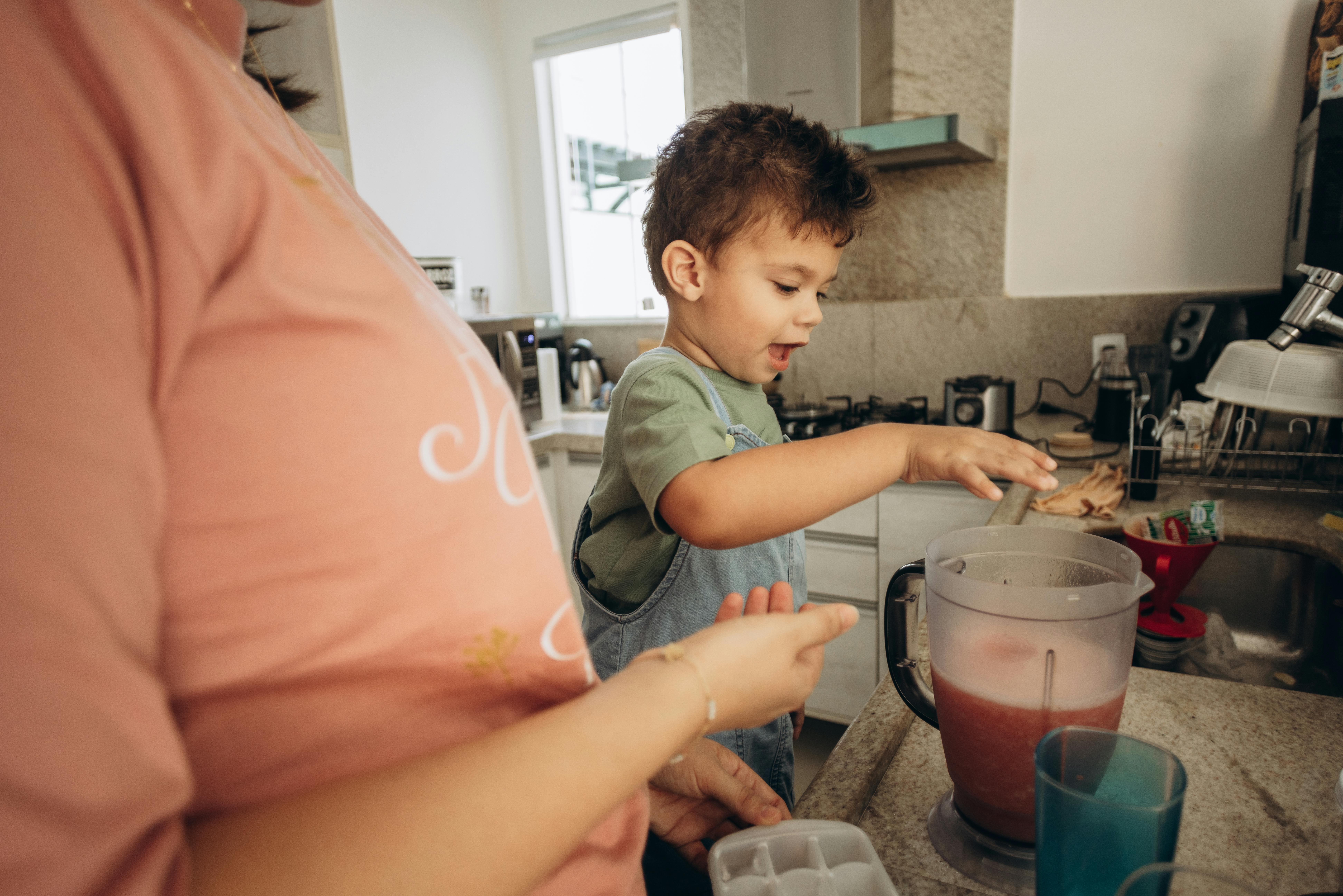 Child helps mother prepare juice in the cozy kitchen setting.