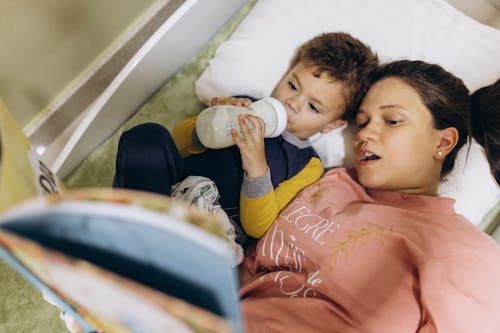 Free Mother Lying Down with Son and Book Stock Photo