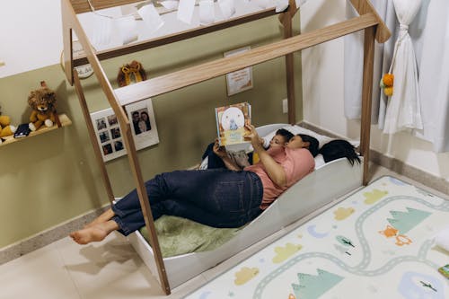 Free Mother Lying Down and Reading Book with Son Stock Photo