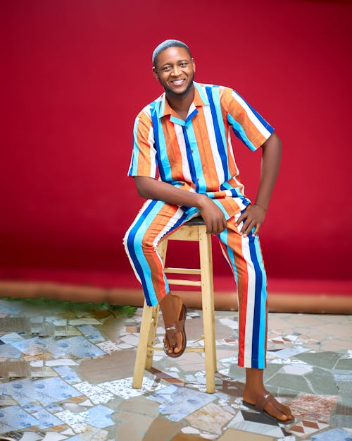 Smiling Man in Colorful, Striped Shirt and Trousers