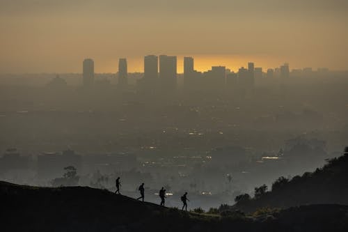 People Walking on Hill over City under Smog