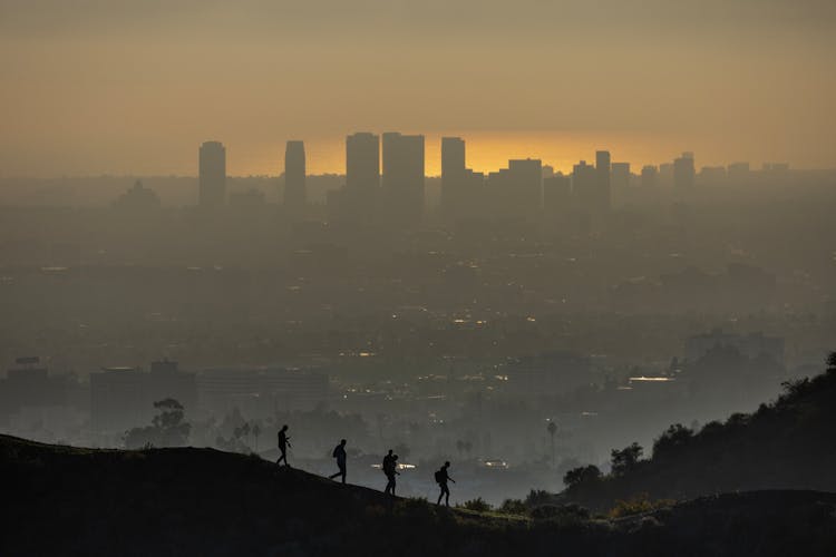 People Walking On Hill Over City Under Smog