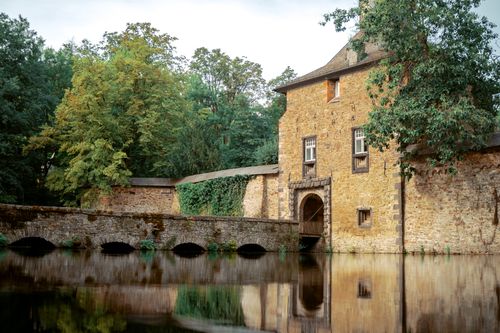 Free Scenic view of a historic stone building by a calm lake in NRW, Germany. Stock Photo