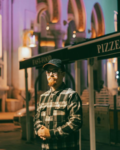 Free Portrait of a man in a checkered shirt and baseball cap at night in Algerian city streets. Stock Photo