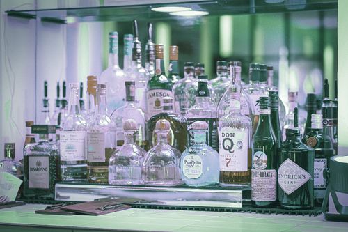 Free A diverse selection of liquor bottles displayed on a bar shelf, showcasing various brands and types. Stock Photo