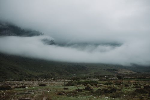 Free A serene mountain valley enveloped in fog and low-lying clouds, creating a mysterious atmosphere. Stock Photo