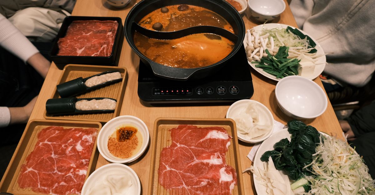 Bubbling spicy Chongqing hotpot with fresh ingredients ready to cook