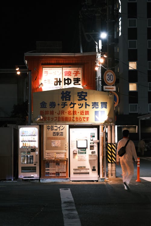 Man Walking past Vending Machines on a Japanese City Street at Night