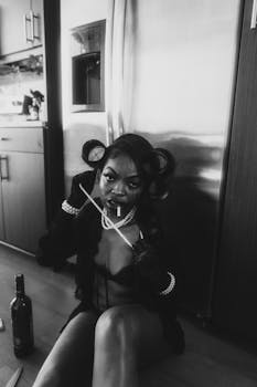 Edgy black and white portrait of a woman sitting indoors with pearls and cigarette.