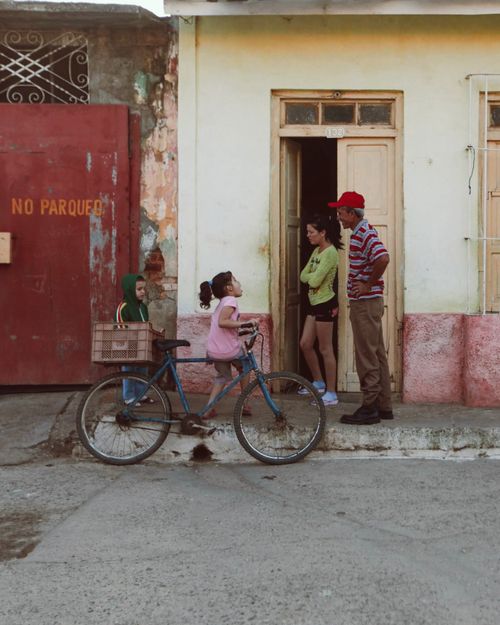 Free Warm family interaction outside a rustic home, featuring a bicycle. Stock Photo